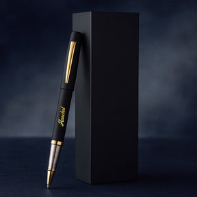 Black pen with gold accents next to a black box on a dark background