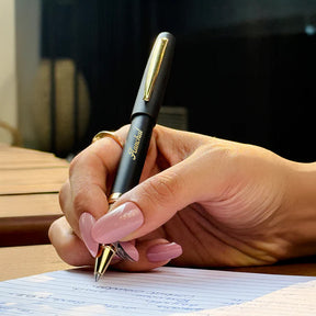 Hand holding a pen with a gold clip over lined paper