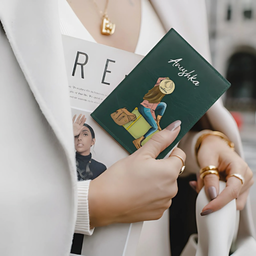 Hand holding a green passport cover with artistic design, wearing a white coat.