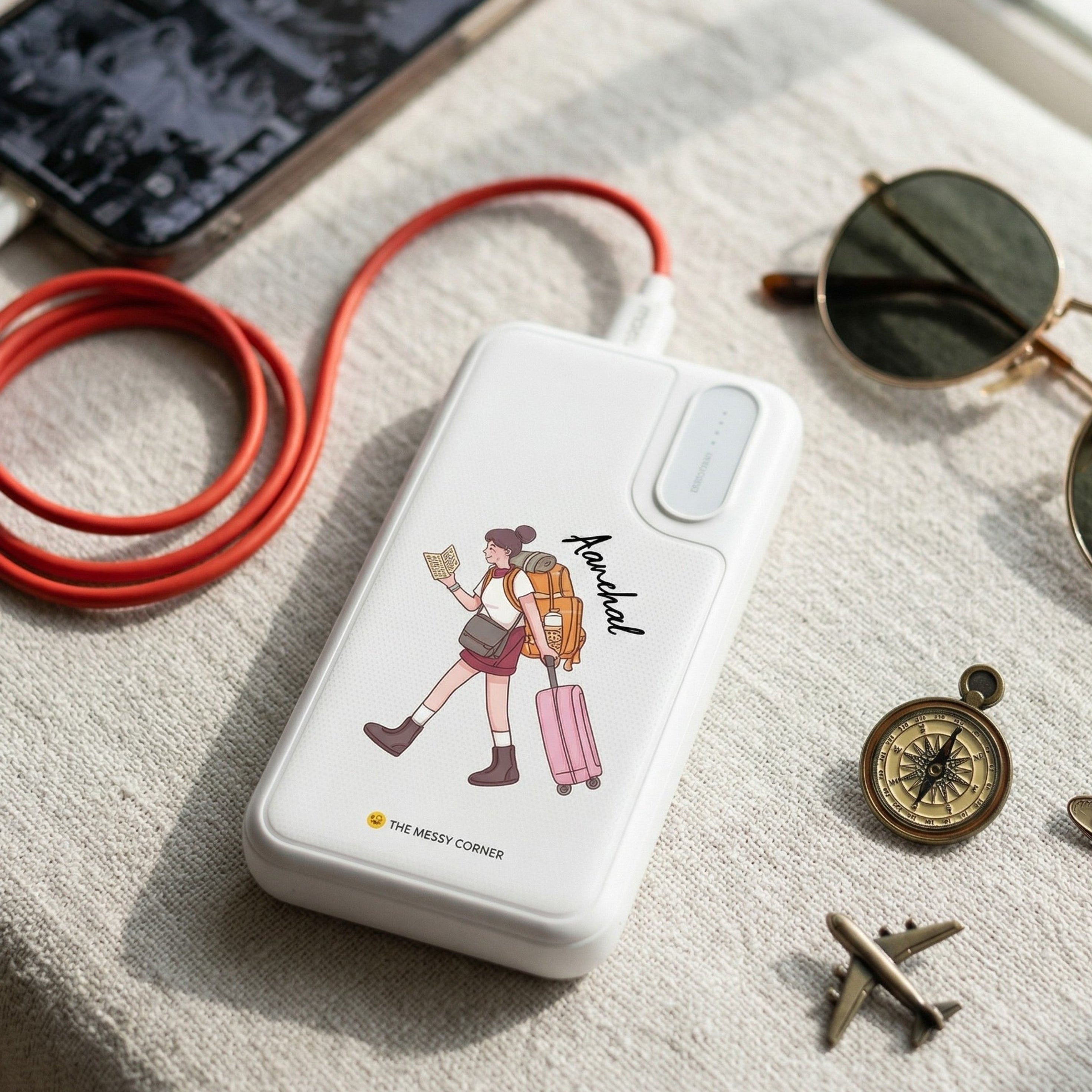 White power bank with a design of a person with a backpack on a textured surface with sunglasses and other items.